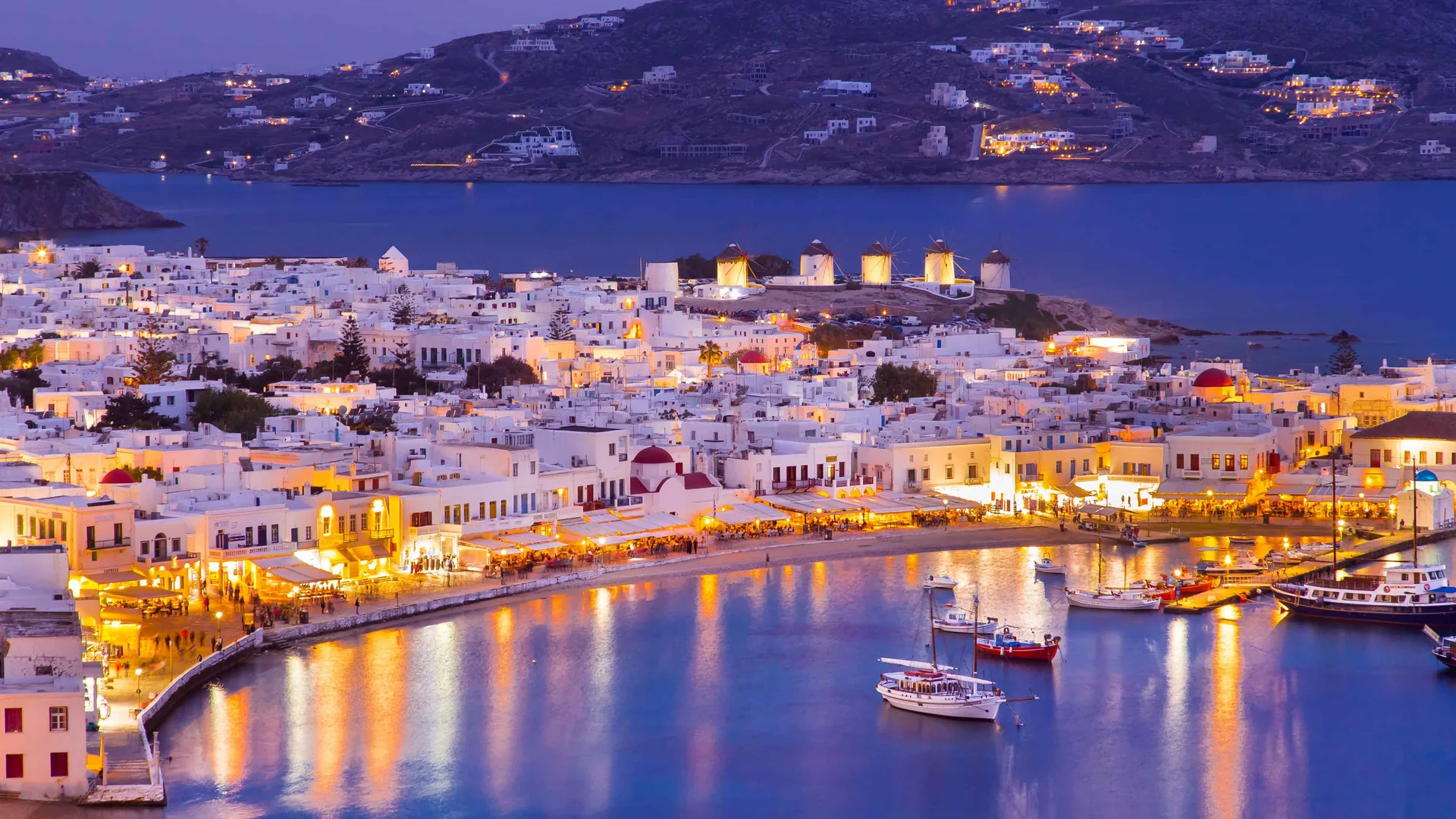 Mykonos Town and its harbour lit up at dusk