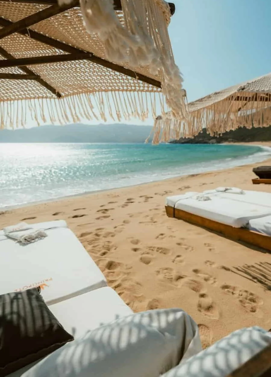 Sunbeds under woven umbrellas on the sand at a Mykonos beach club
