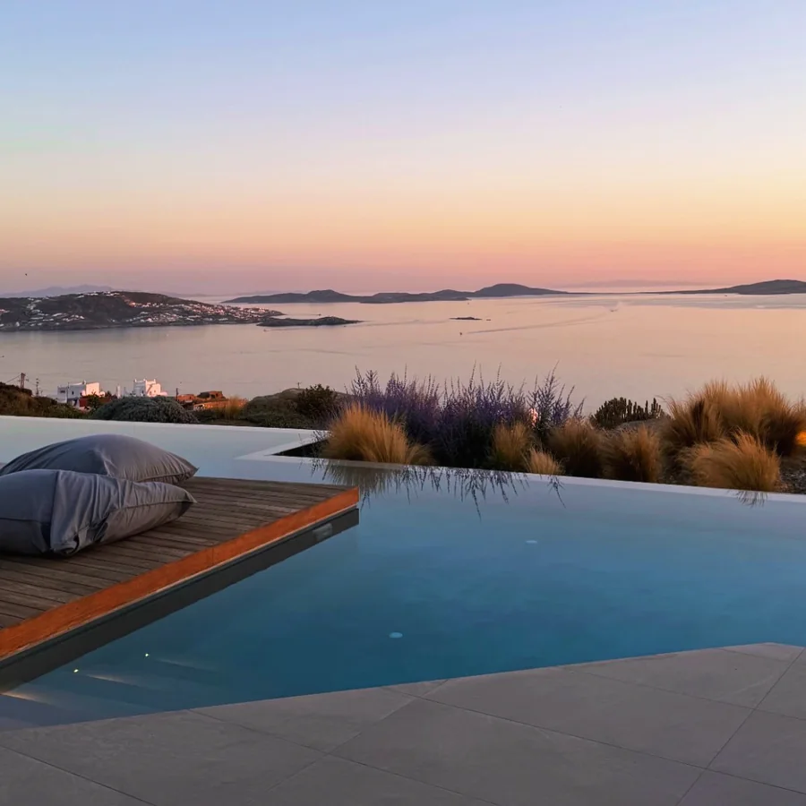 Infinity pool and daybed above the bay of Mykonos at sunset