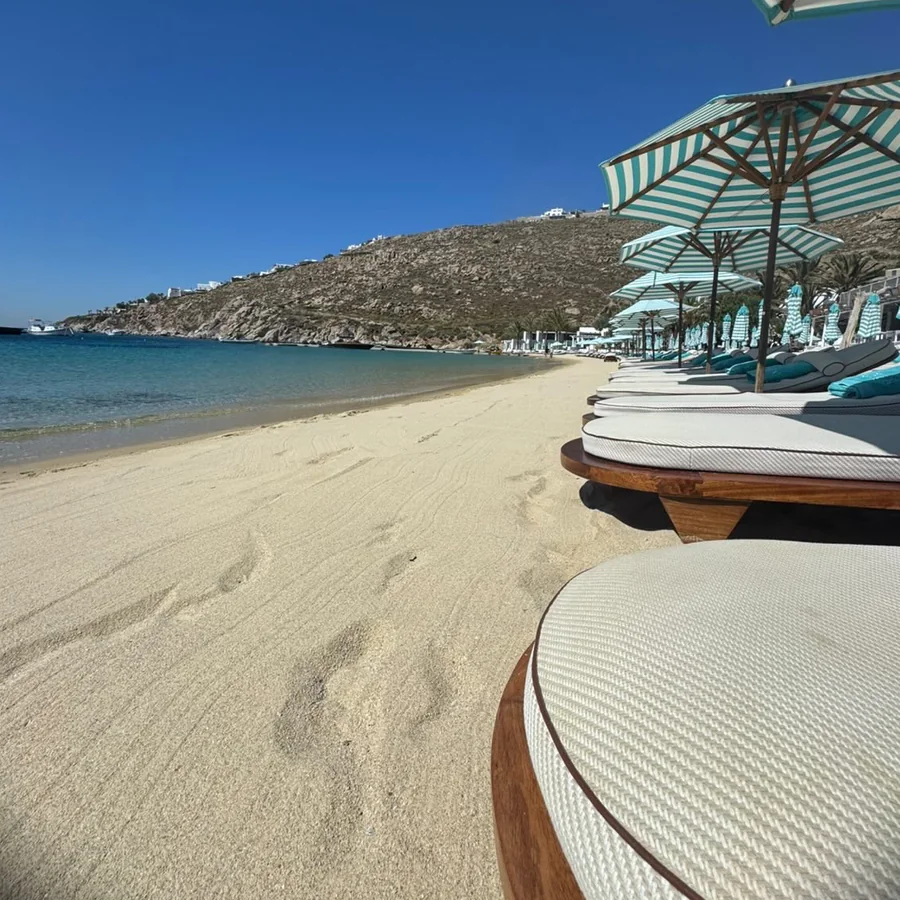 Sunbeds and striped umbrellas along a sandy beach in Mykonos