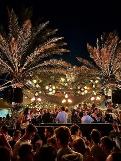 Open-air club in Mykonos at night under lit palm trees
